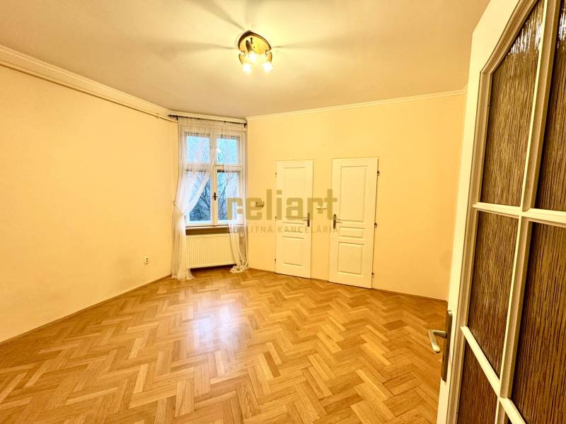 A room in a 4-room apartment with a wooden decor floor, a curtain, and two doors.
