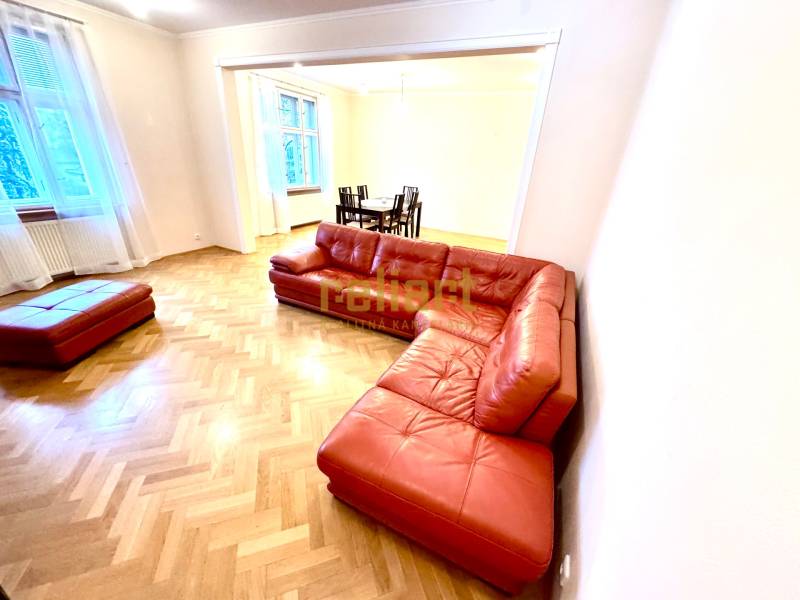 Living room of a 4-room apartment with a red sofa and a wooden decor floor.