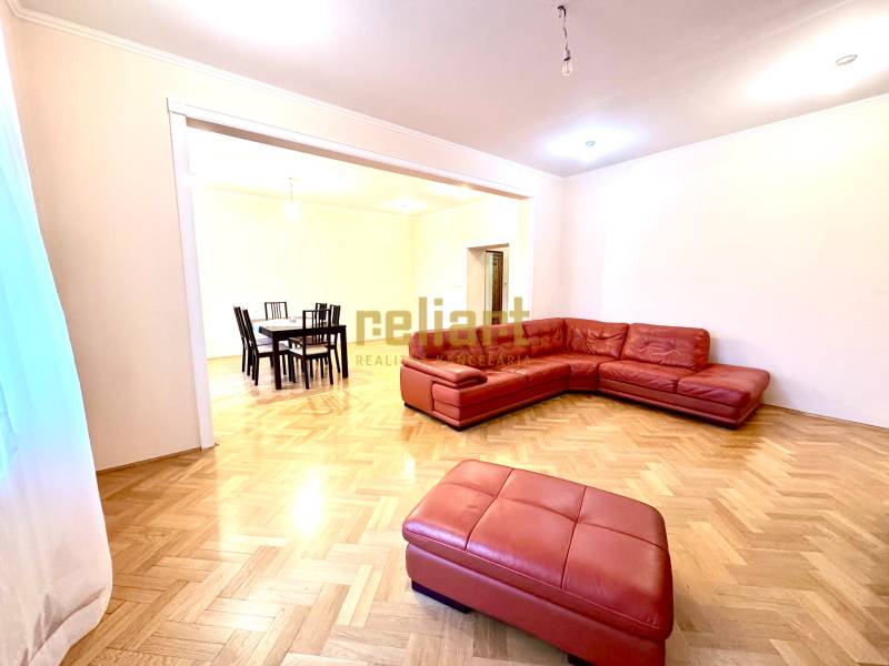 Living room in a four-room apartment with a red sofa and a wooden decor floor.