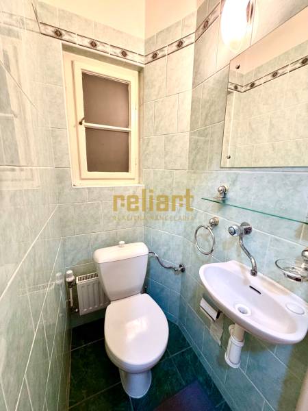 Bathroom in a 4-room apartment with a sink, toilet, and window with ceramic tiles.