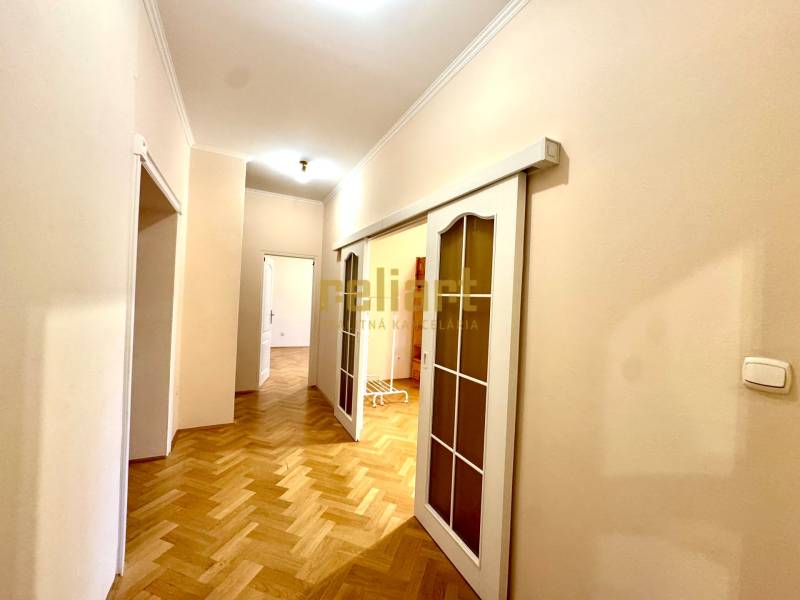 A hallway with sliding doors in a 4-room apartment and a floor with a wood decor.