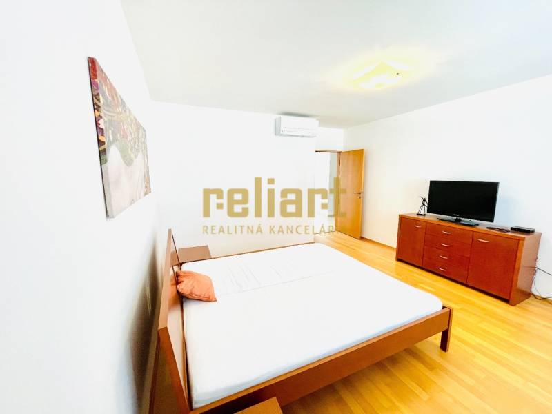 Bright bedroom in a 4-room apartment with wood-patterned flooring, a bed, and a dresser.