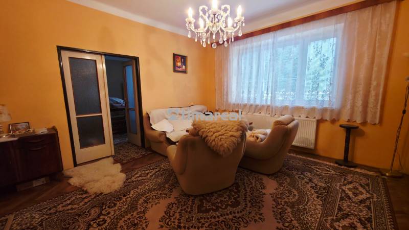 Living room in a family house with carpets, a chandelier, and comfortable armchairs.