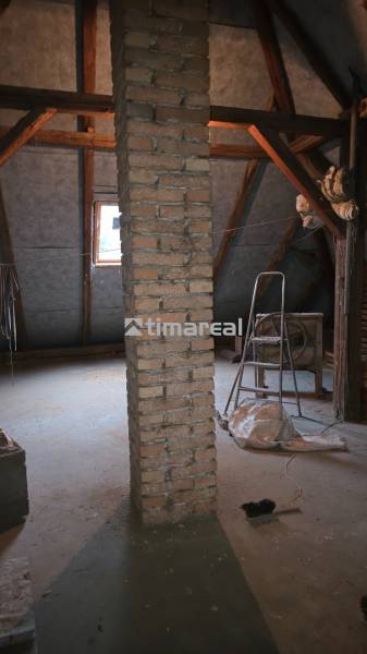 Attic of a family house with a brick pillar, steps, and a window in the roof section.