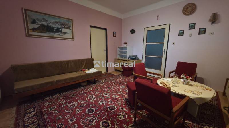 Living room in a family house with a red carpet and wooden furniture.