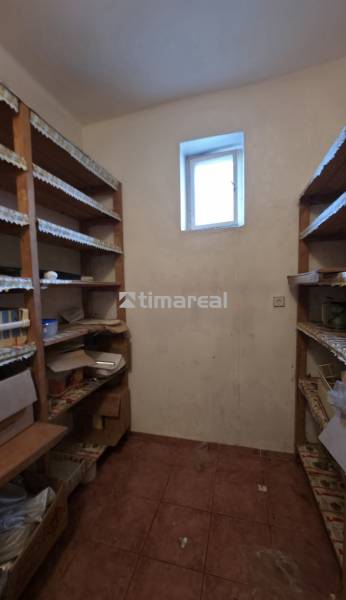 A pantry in a family house with shelves and a small window, suitable for storage.