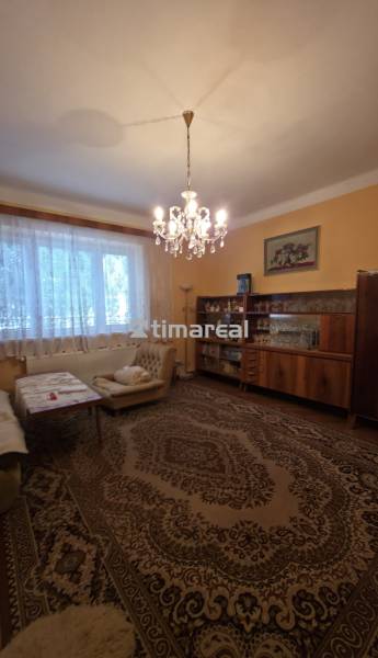 Living room in a family house with a chandelier and furniture, floor with a decorative carpet.