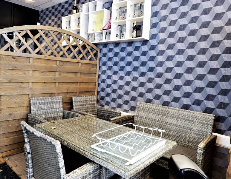 Wicker furniture in commercial spaces in front of a wall with a geometric pattern and a wooden screen.