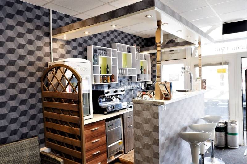 Interior of commercial spaces with a bar counter, decorative walls, and bar stools.