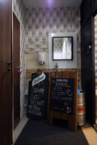 Interior commercial spaces with a mirror, sink, and boards with beverage offerings.