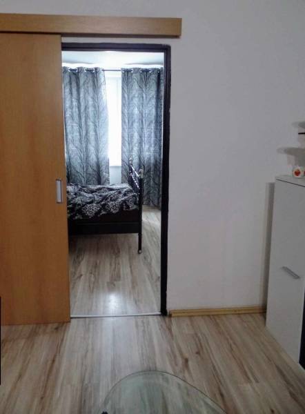 Interior with wood-patterned flooring, sliding doors, and black-and-white curtains in a 3-room apartment.