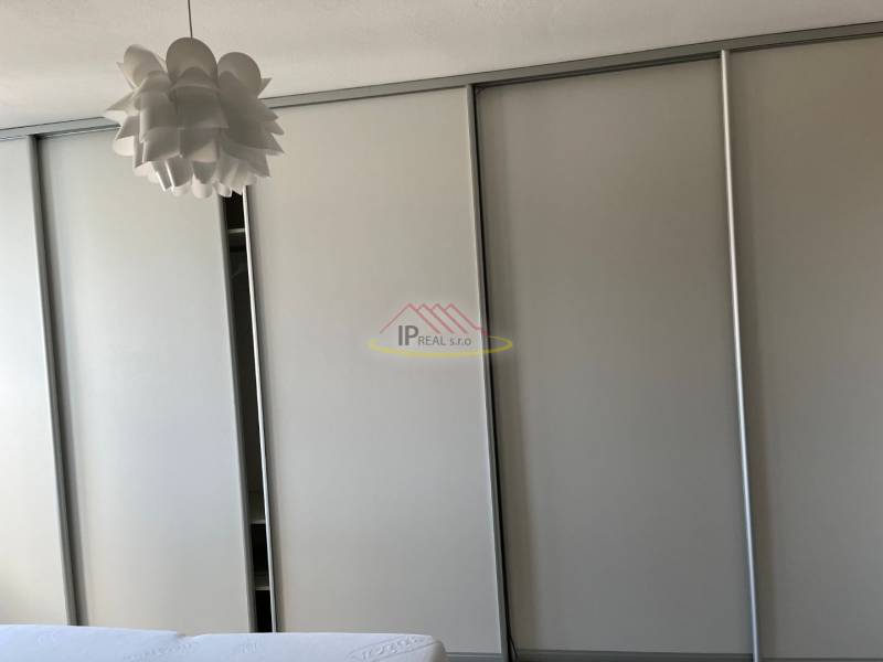 A built-in wardrobe with a light decor and an original ceiling chandelier in a 4-room apartment.