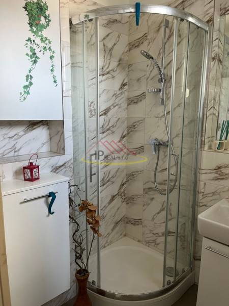 Compact bathroom with a shower and marble tiles in a 4-room apartment.