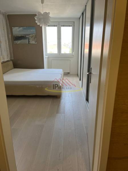 A bedroom with light furniture, a large window, and a floor with a wooden decor in a 4-room apartment.