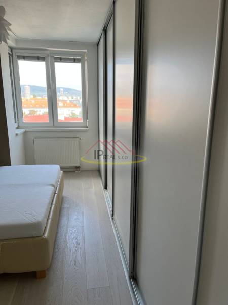 Bedroom in a 4-room apartment with a bed, wood-patterned floor, and a wardrobe.