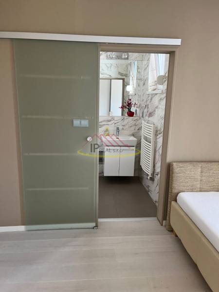 A bathroom in a 4-room apartment with a wooden decor floor and glass doors.