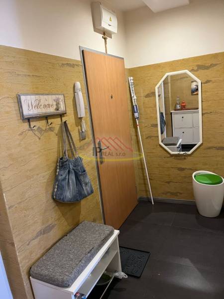Interior of the hallway in a 4-room apartment with a coat rack, bench, and mirror.