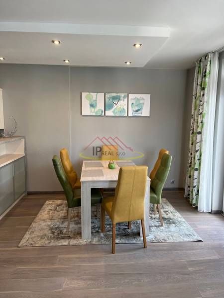 Dining area in a 4-room apartment with colorful chairs and a wooden-patterned floor.