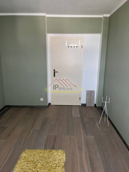 A place in a 4-room apartment with a wooden decor floor and a green wall.