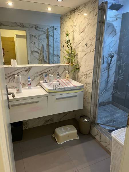 Luxury bathroom with a shower and marble tiles in a 4-room apartment.