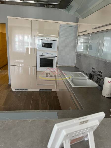 A kitchen in a 4-room apartment with a corner-positioned kitchen unit and a floor with a wooden decor.