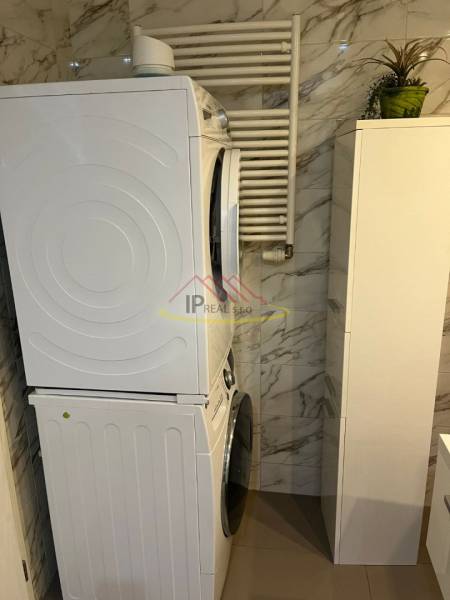 Washer-dryer in the bathroom of a 4-room apartment, marble tiles on the walls.