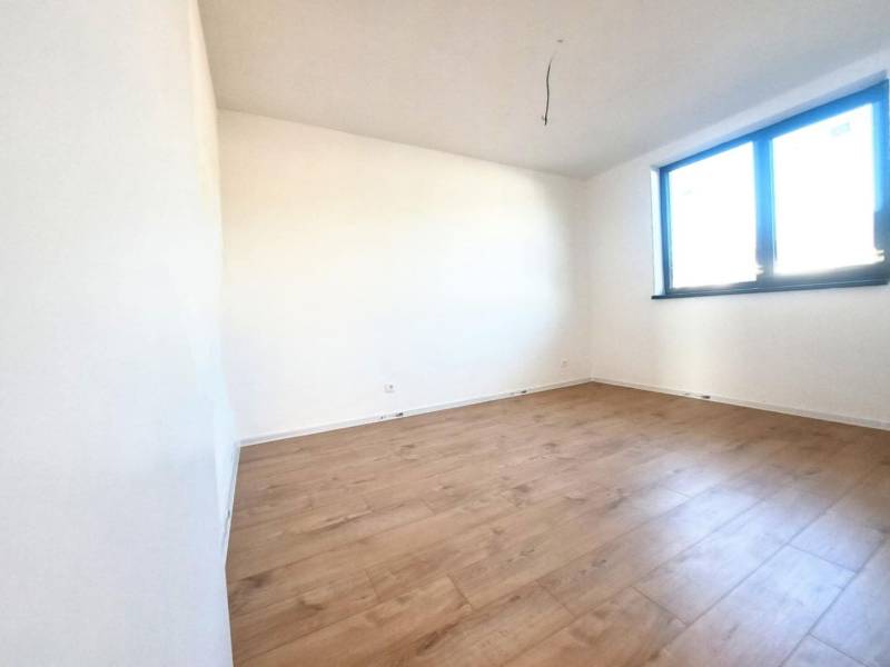 An empty room with a wood-patterned floor and a large window in a family house.