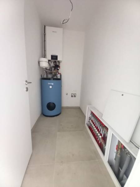 Technical room in a family house with a gas boiler and underfloor heating distributors.