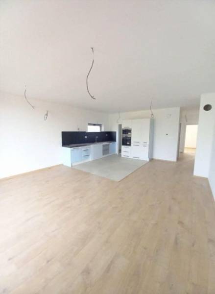 A kitchen with white cabinets, a dark countertop, and a wood-patterned floor.