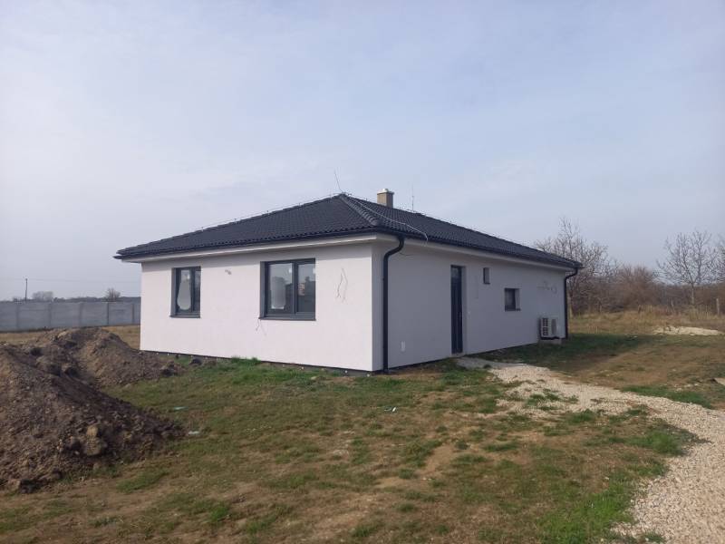 A family house in Galanta with a white facade stands on a grassy plot.