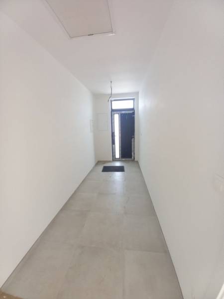 A narrow white hallway with tiles and entrance doors in a family house.