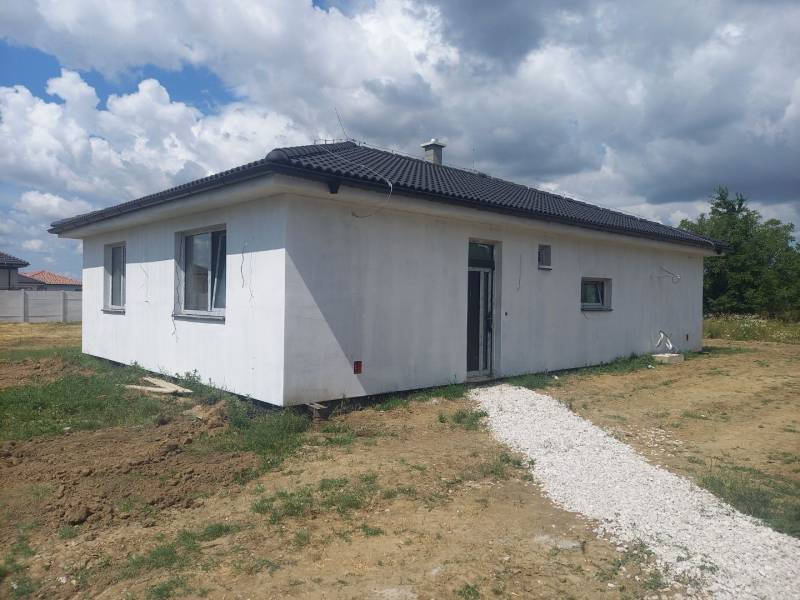 A family house in Galanta with a white exterior on a grassy plot under a cloudy sky.