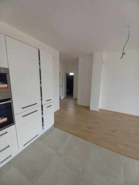 The kitchen area of a family house with white cabinets and a floor with a wooden decor.