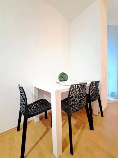 Dining area in a 2-room apartment with black chairs and a white table.