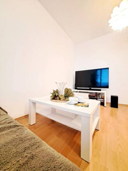 Living room in a two-room apartment with a wooden decor floor and a white table.