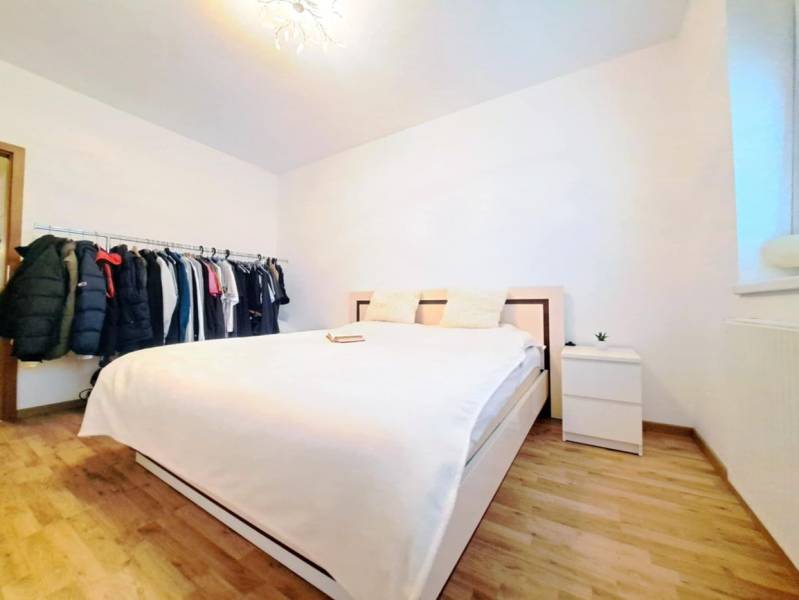 Bright bedroom with a wardrobe and a bed, complemented by a wooden decor floor.
