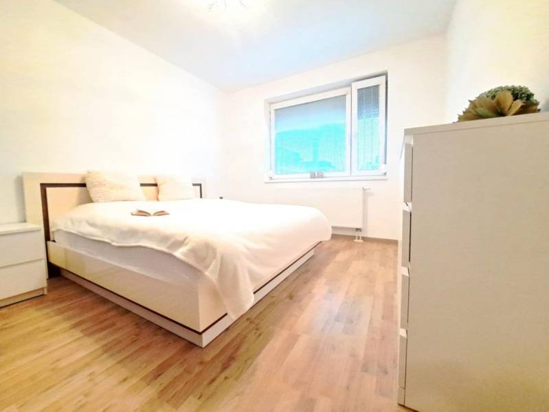 Bedroom in a 2-room apartment with wood-patterned flooring and a large bed.