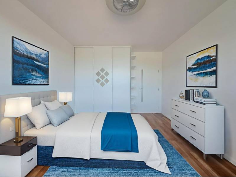 A bright bedroom with blue accents and wood-patterned flooring in a 2-room apartment.