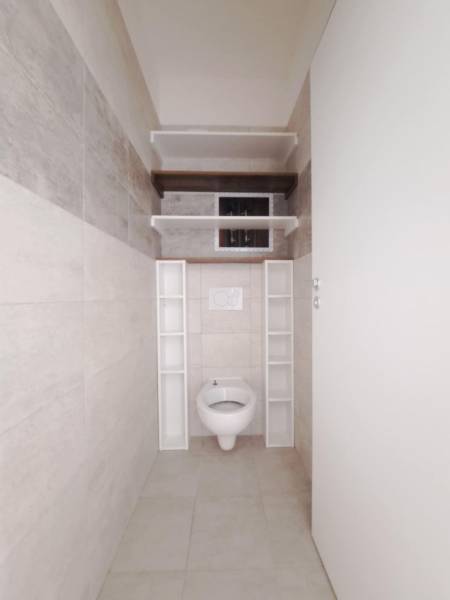Bathroom in a 2-room apartment with a toilet and storage shelves.