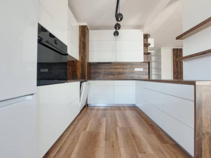 A kitchen in a 2-room apartment with white cabinets and a wood-patterned floor.