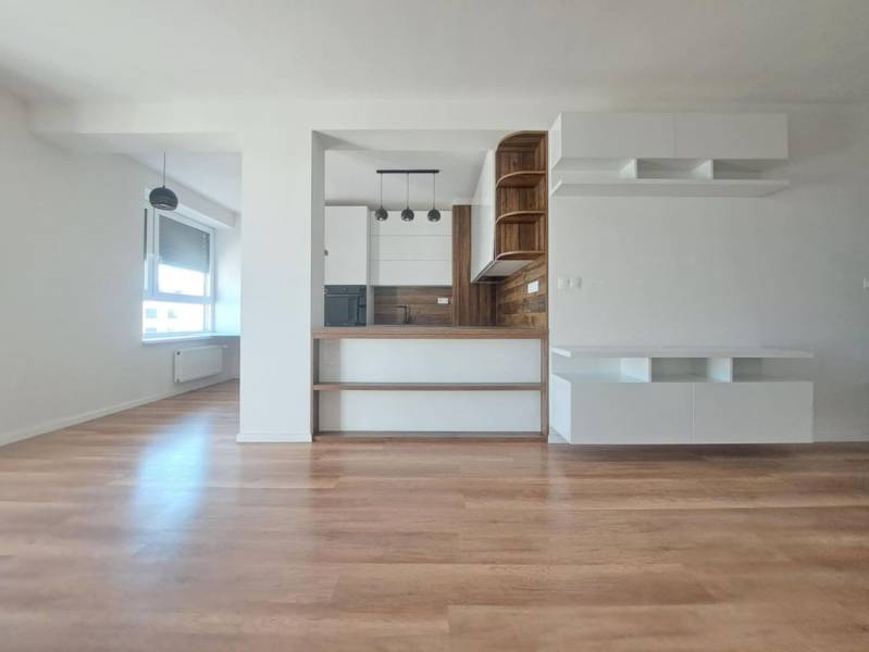 Kitchen area in a 2-room apartment with a wood-patterned floor and white cabinets.