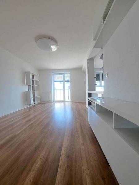 Living space in a 2-room apartment with a wooden decor floor and light-colored walls.