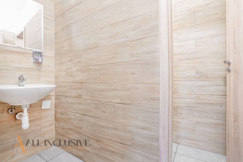 An office interior with a sink, wooden walls, and open doors.
