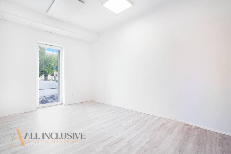 An empty office with a wooden floor and a large window.