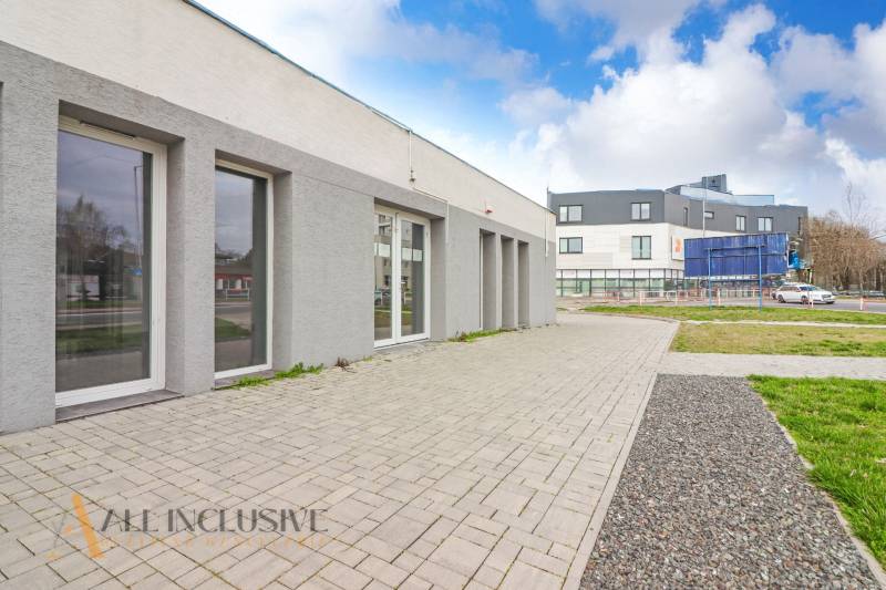 On Vajanského Street, next to commercial spaces with modern architecture and paved sidewalks.