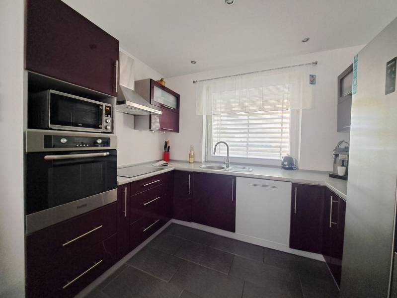 A kitchen unit in a family house with purple cabinets and built-in appliances.