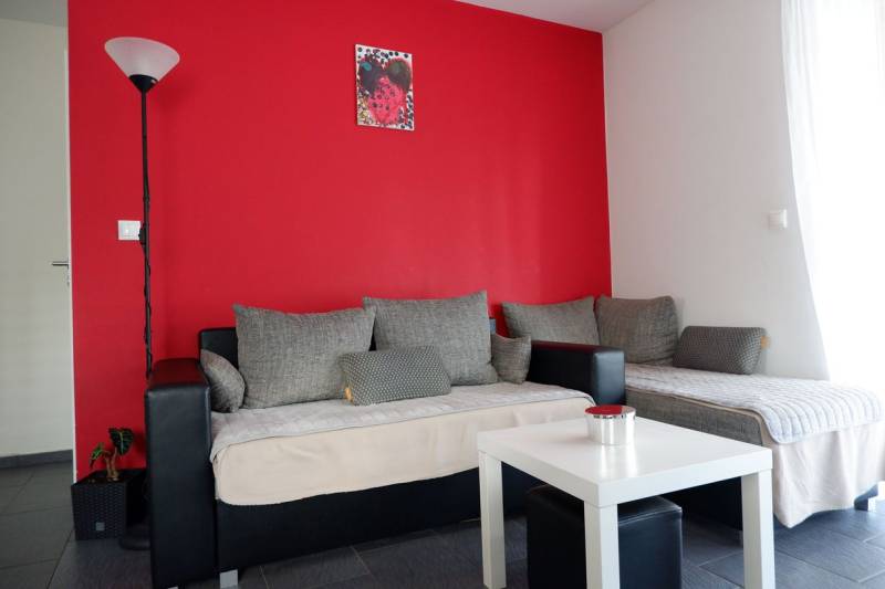 Interior of a family house with gray sofas, a red wall, and a white table.