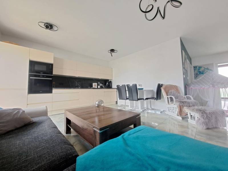 Living room in a family house with an open kitchen and dining table. Floor with wooden decor.