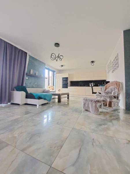 Living room with large windows and light tiles in a family house.
