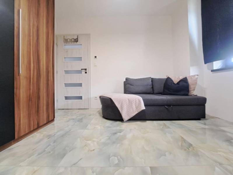 A room in a family house with a sofa, a cabinet, a door, and a floor with a marble design.